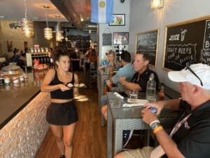 A woman walking in front of people at an indoor restaurant.