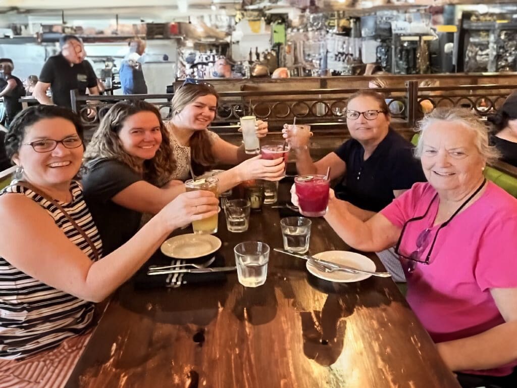 Four women toasting with drinks at a restaurant.