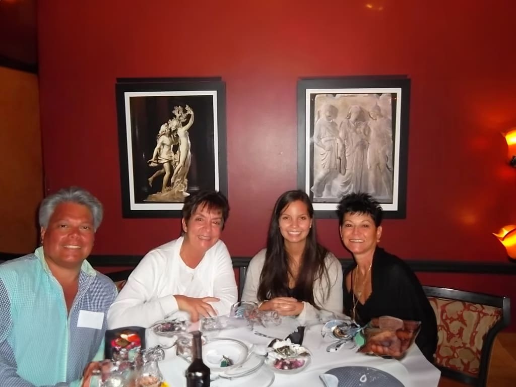 Four people dining with framed artwork.